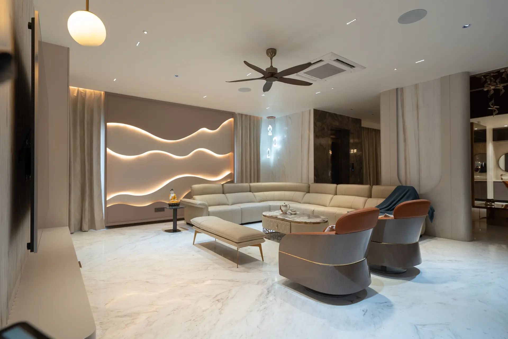 A spacious living room with a backlit wave wall and curved sectional, designed by Simplify Home