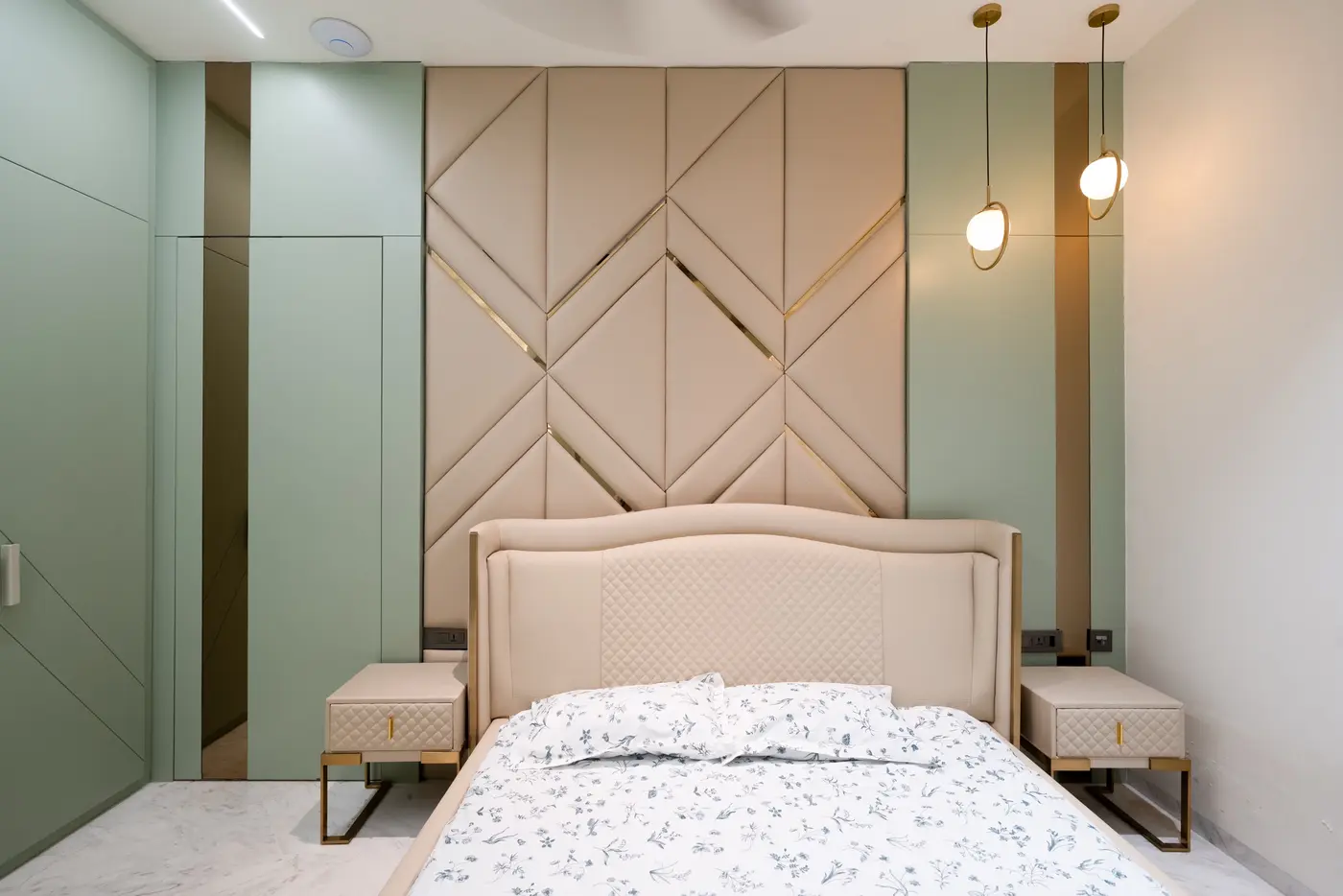 Bedroom in soft sage and beige with a chevron-panelled headboard and brass accents