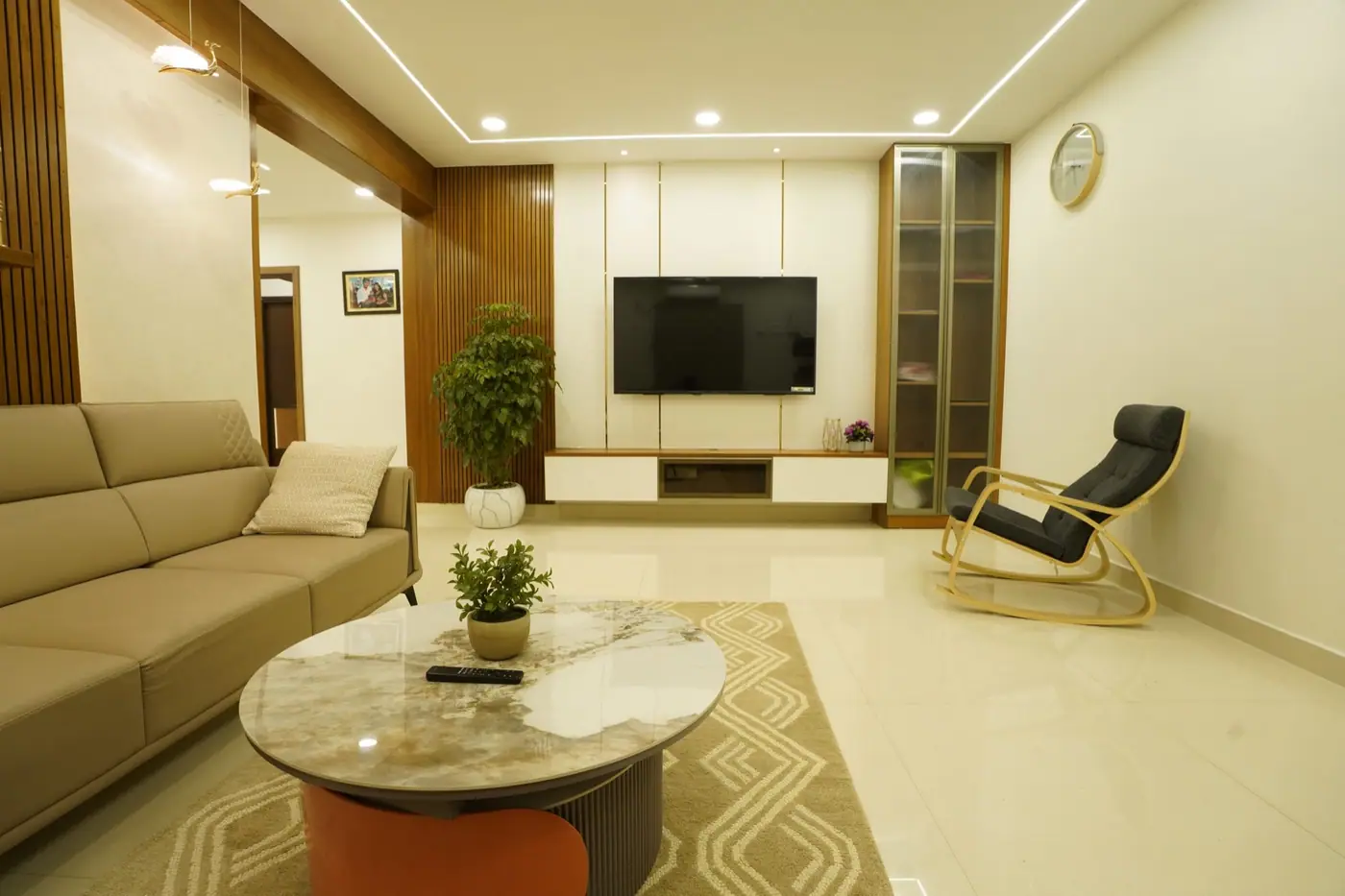 Living room with a white TV unit, wood-finish tall storage, wall panelling and cove lighting