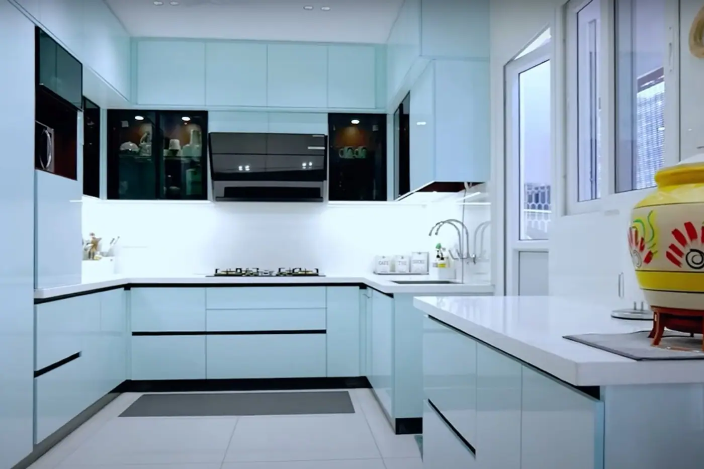 U-shaped modular kitchen with light laminate shutters, glass-front wall units and organised storage